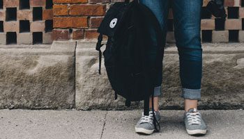 Image of lower half of person holding a backpack